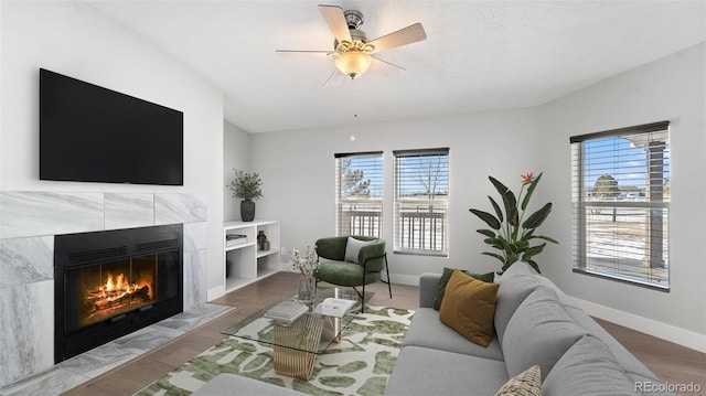 living room featuring a tiled fireplace, plenty of natural light, hardwood / wood-style flooring, and ceiling fan