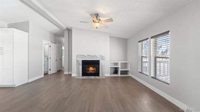 unfurnished living room featuring lofted ceiling, wood-type flooring, a textured ceiling, ceiling fan, and a high end fireplace