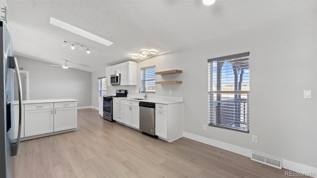kitchen with white cabinetry, appliances with stainless steel finishes, sink, and light hardwood / wood-style floors