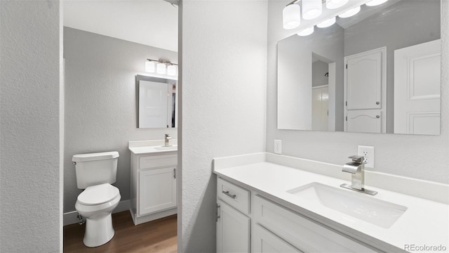 bathroom featuring vanity, wood-type flooring, and toilet