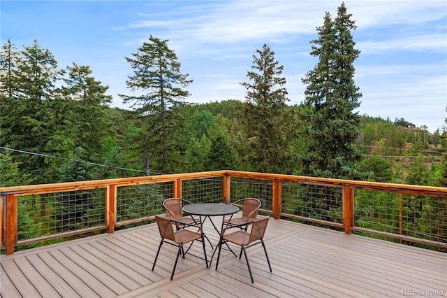 6773 Snowshoe Trl, Evergreen, CO 80439 - wooden deck featuring a forest view and outdoor dining space