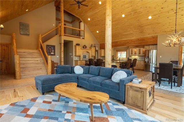 living room featuring high vaulted ceiling, ceiling fan with notable chandelier, light hardwood / wood-style floors, and wooden ceiling