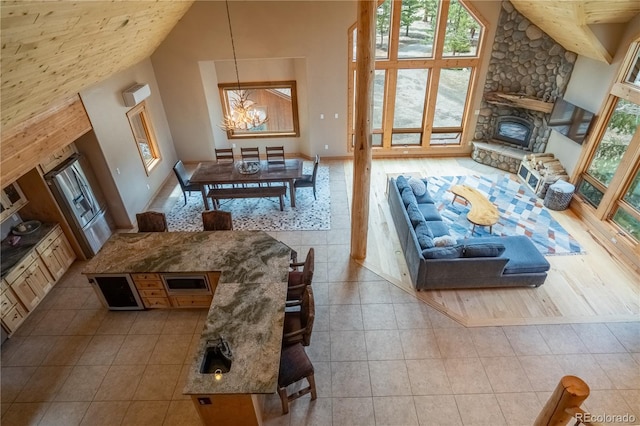 tiled living room featuring a healthy amount of sunlight, an inviting chandelier, a fireplace, and high vaulted ceiling