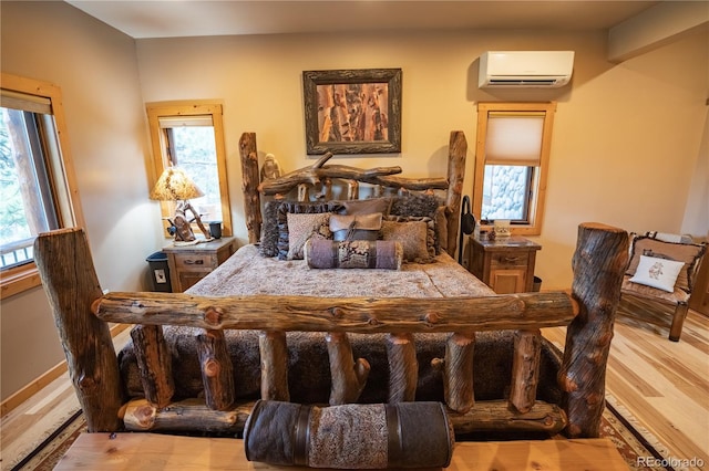 bedroom featuring multiple windows, a wall unit AC, and light hardwood / wood-style flooring