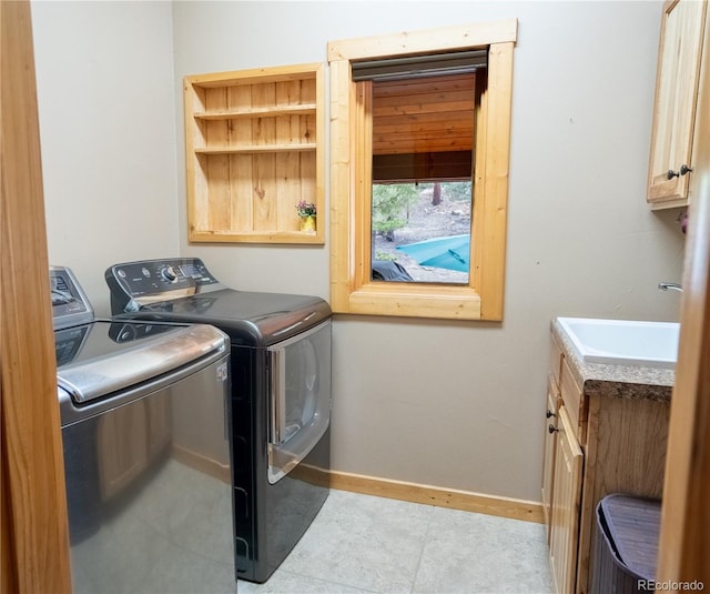 laundry room with washing machine and clothes dryer, cabinet space, baseboards, and a sink