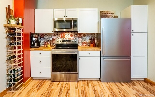 kitchen with stainless steel appliances, light wood finished floors, decorative backsplash, and white cabinetry