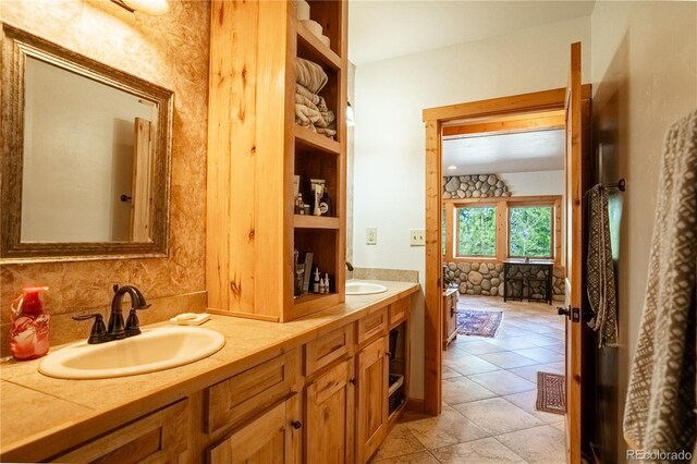 full bath with a sink, double vanity, and tile patterned floors