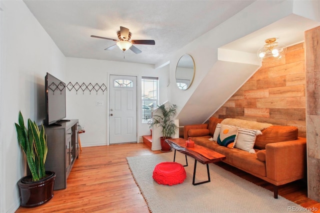 living room featuring light wood-type flooring, a textured ceiling, and a ceiling fan