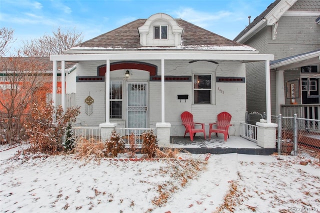 view of front of property featuring a porch, a shingled roof, and fence