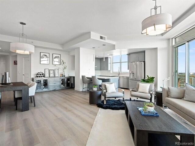 2001 Lincoln St Unit 1822, Denver, CO 80202 - living room featuring visible vents, a healthy amount of sunlight, and light wood-type flooring