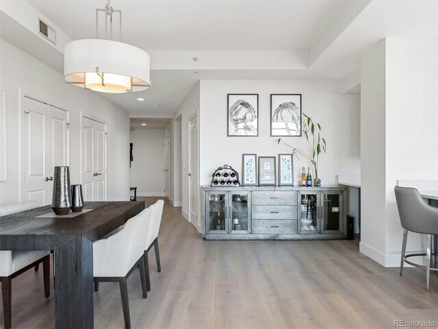 2001 Lincoln St Unit 1822, Denver, CO 80202 - dining area featuring a bar, baseboards, visible vents, and wood finished floors