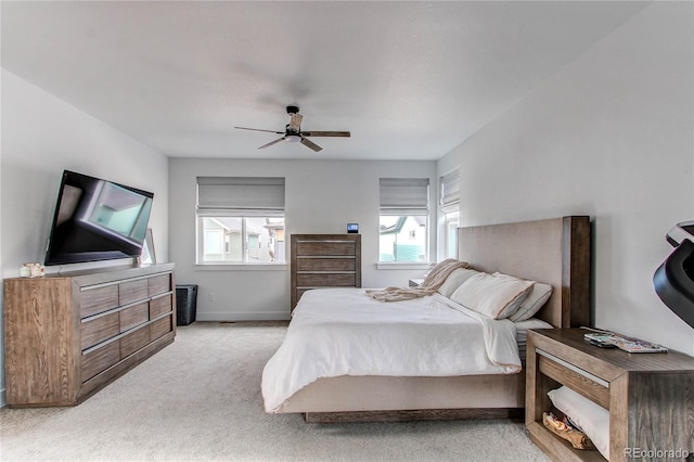 bedroom featuring ceiling fan, light carpet, and multiple windows