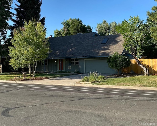 view of front of property with a garage, concrete driveway, a shingled roof, and fence