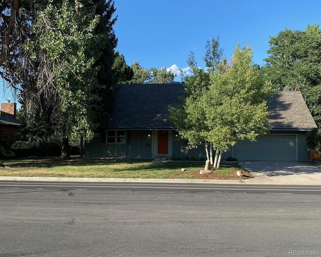 view of front of home featuring driveway, roof with shingles, a garage, and a front yard