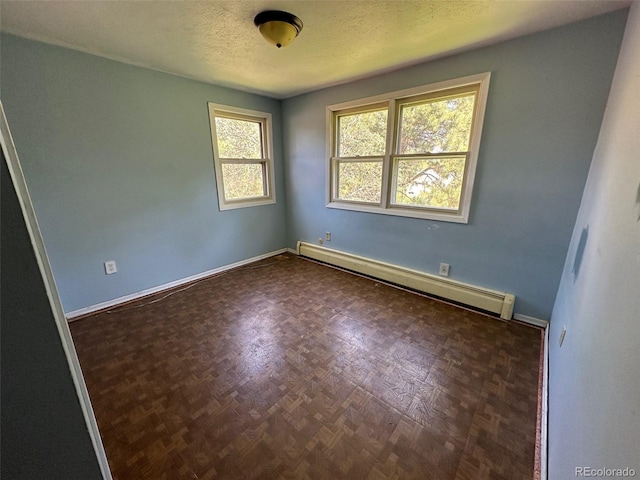 empty room featuring a textured ceiling, a baseboard radiator, and baseboards