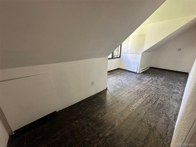 additional living space featuring dark wood-type flooring and vaulted ceiling