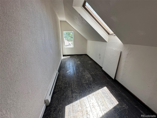 bonus room featuring a baseboard radiator, vaulted ceiling with skylight, and a textured wall