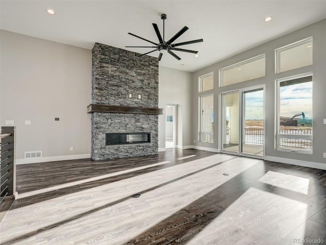 living room with hardwood / wood-style flooring, ceiling fan, and a stone fireplace