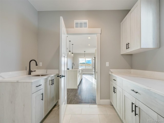 interior space with white cabinetry, sink, and light tile patterned floors