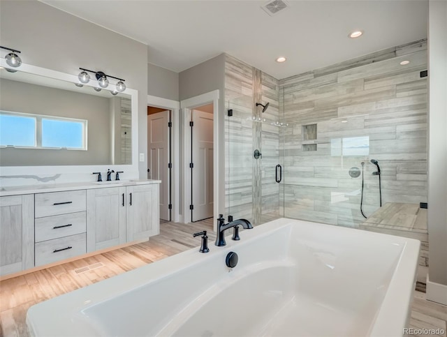 bathroom with hardwood / wood-style floors, vanity, and shower with separate bathtub