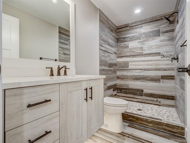 bathroom featuring tiled shower, wood-type flooring, vanity, and toilet