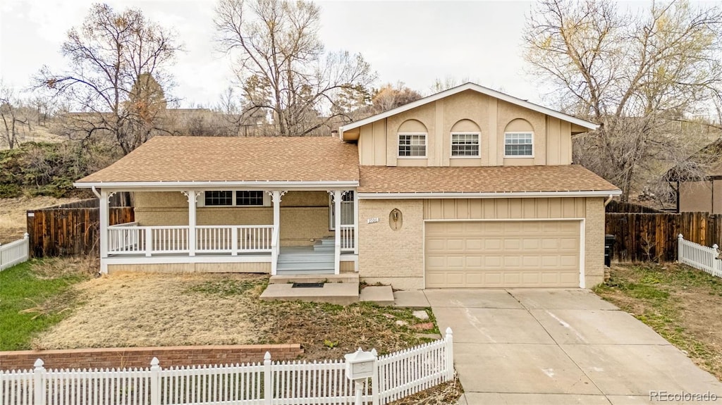 2706 Penacho Cir, Colorado Springs, CO 80917 - split level home with a porch, an attached garage, concrete driveway, a fenced front yard, and a shingled roof