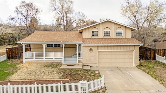 2706 Penacho Cir, Colorado Springs, CO 80917 - split level home with a porch, an attached garage, concrete driveway, a fenced front yard, and a shingled roof