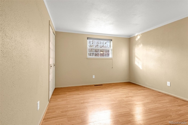 2706 Penacho Cir, Colorado Springs, CO 80917 - empty room featuring light wood-type flooring, a textured wall, baseboards, and ornamental molding