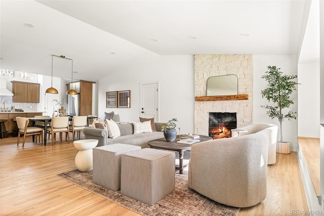 13416 W 22nd Pl, Golden, CO 80401 - living area with vaulted ceiling, light wood finished floors, and a stone fireplace