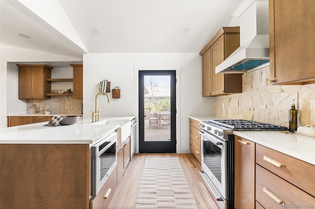 13416 W 22nd Pl, Golden, CO 80401 - kitchen featuring open shelves, wall chimney exhaust hood, brown cabinets, a sink, and appliances with stainless steel finishes