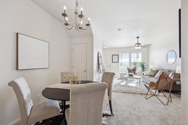 dining space with carpet flooring, ceiling fan with notable chandelier, and vaulted ceiling