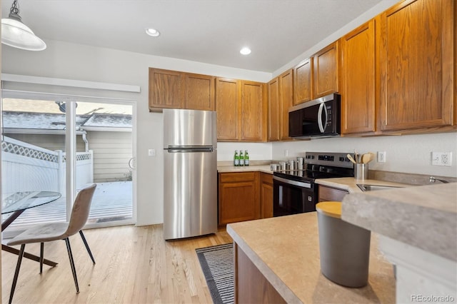 kitchen featuring decorative light fixtures, stainless steel appliances, and light hardwood / wood-style floors