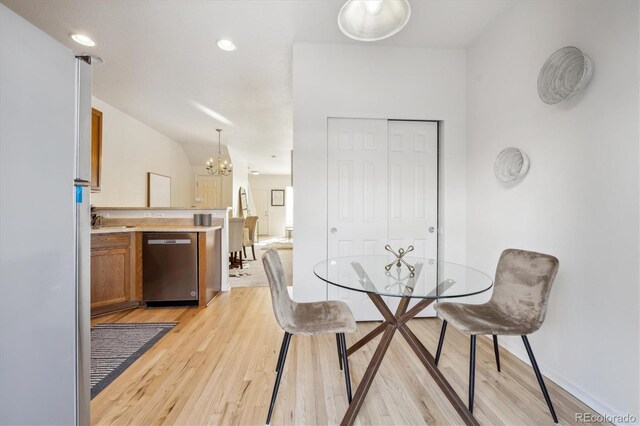 dining space featuring light wood-type flooring, sink, and a chandelier