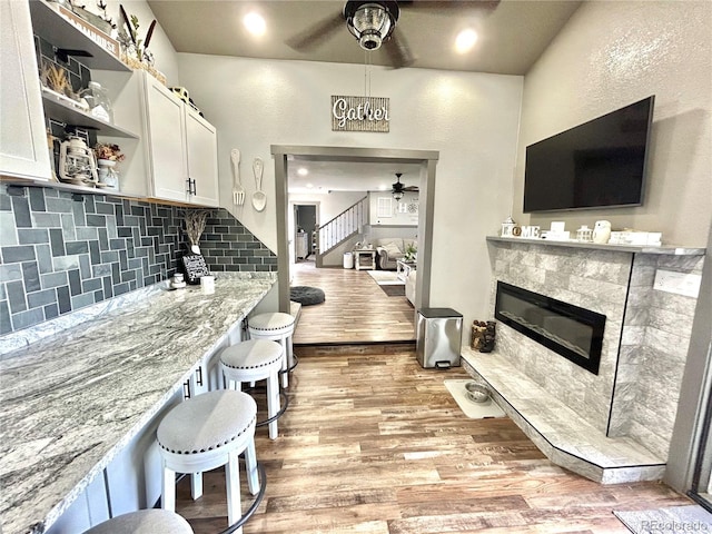 kitchen featuring ceiling fan, open shelves, a premium fireplace, light wood-type flooring, and white cabinetry
