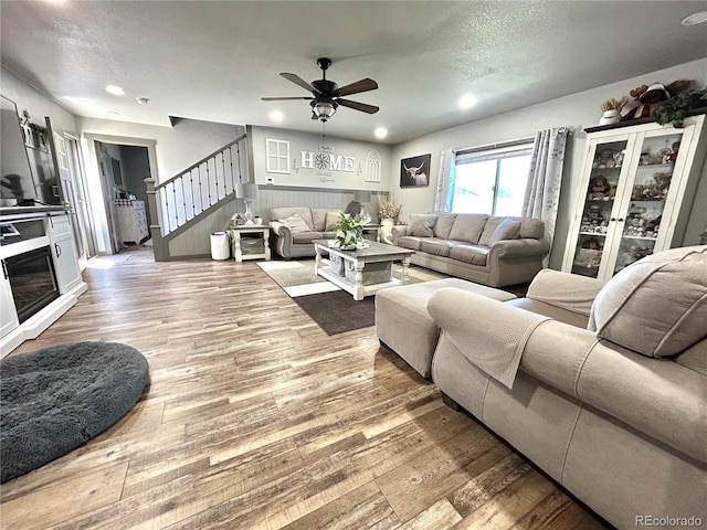 living area with stairs, ceiling fan, wood finished floors, recessed lighting, and a textured ceiling