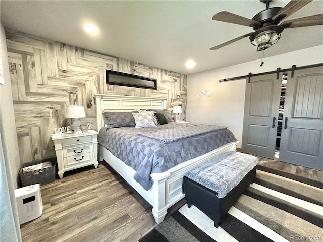 bedroom featuring a barn door, wood finished floors, ceiling fan, and recessed lighting