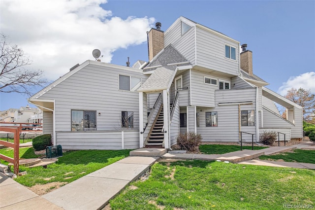 17094 E Tennessee Dr Unit 212, Aurora, CO 80017 - view of front of home featuring a chimney, stairs, a front lawn, and roof with shingles
