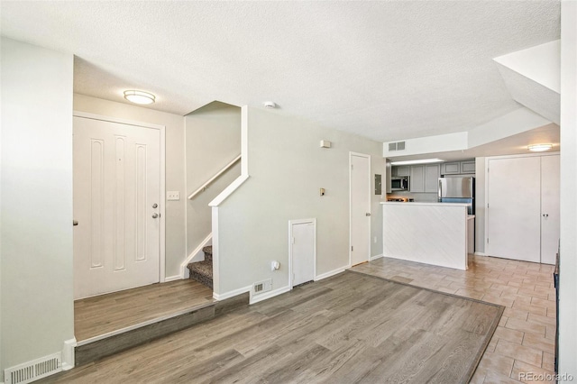 17094 E Tennessee Dr Unit 212, Aurora, CO 80017 - unfurnished living room with a textured ceiling, stairway, baseboards, and light wood-style floors