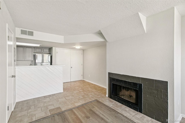 17094 E Tennessee Dr Unit 212, Aurora, CO 80017 - unfurnished living room featuring a fireplace, a textured ceiling, baseboards, and light stone finish floors