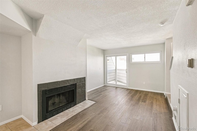 17094 E Tennessee Dr Unit 212, Aurora, CO 80017 - unfurnished living room featuring a tiled fireplace, wood finished floors, a textured ceiling, and baseboards