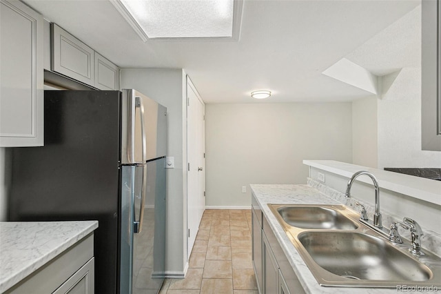 17094 E Tennessee Dr Unit 212, Aurora, CO 80017 - kitchen featuring a sink, freestanding refrigerator, light countertops, gray cabinetry, and baseboards