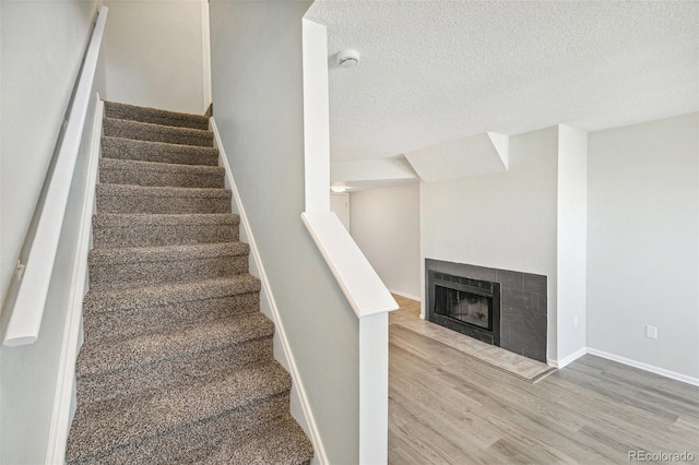 17094 E Tennessee Dr Unit 212, Aurora, CO 80017 - stairway featuring wood finished floors, a textured ceiling, baseboards, and a fireplace