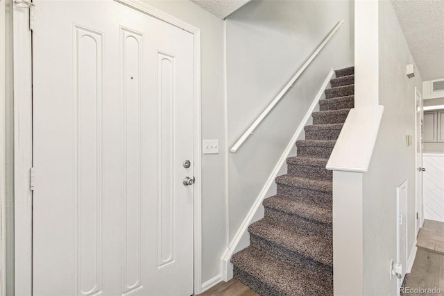 17094 E Tennessee Dr Unit 212, Aurora, CO 80017 - stairs featuring wood finished floors, a textured ceiling, and baseboards
