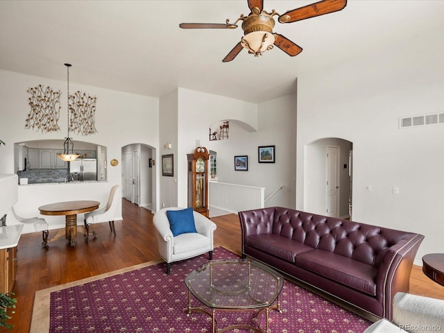 living room featuring visible vents, arched walkways, a ceiling fan, and wood finished floors