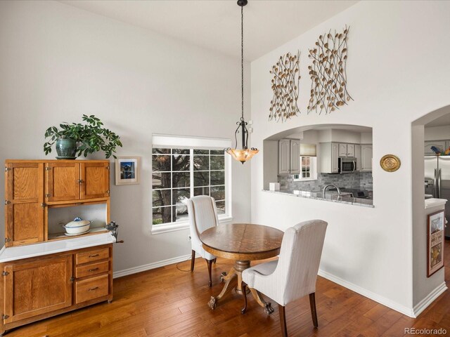 dining room featuring baseboards, arched walkways, and wood finished floors
