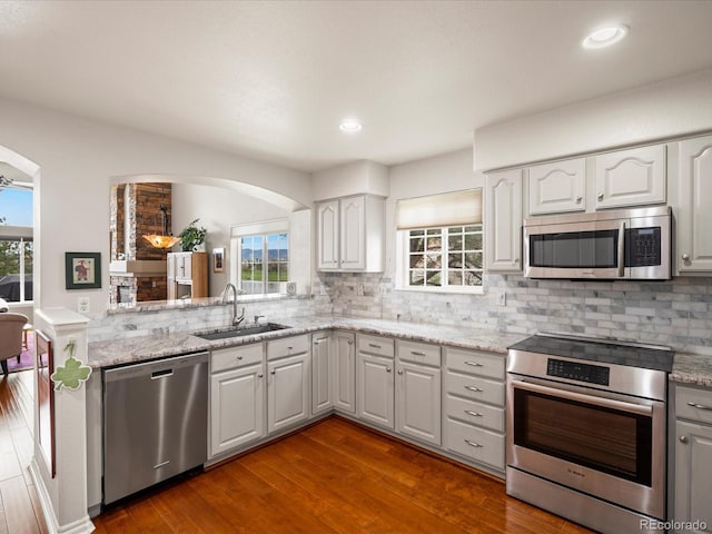 kitchen featuring arched walkways, appliances with stainless steel finishes, a wealth of natural light, and a sink