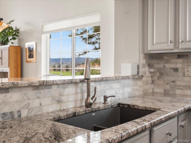 kitchen with a sink, tasteful backsplash, light stone countertops, and a mountain view