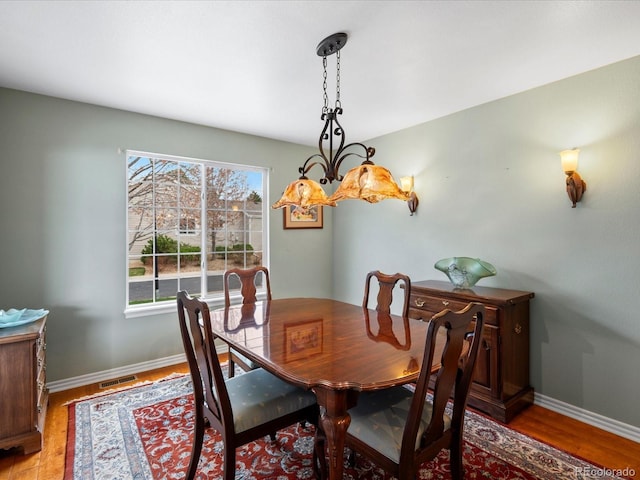 dining space with baseboards, visible vents, and light wood-type flooring