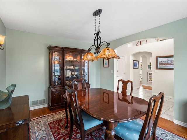 dining area with arched walkways, tile patterned flooring, and visible vents