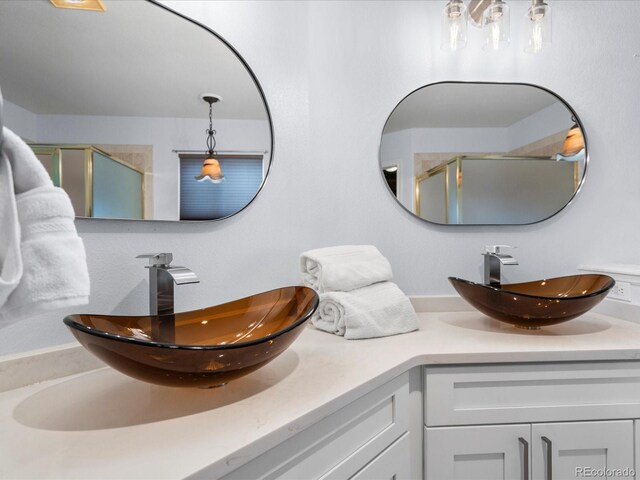 full bathroom featuring double vanity, a sink, and a shower stall
